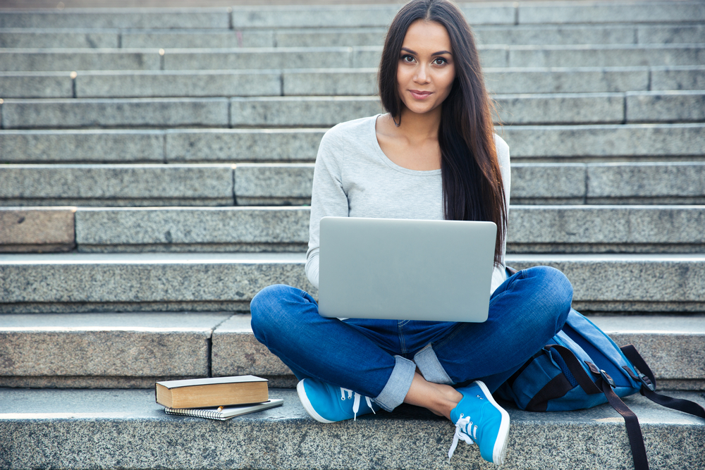 girl sitting on steps outside with laptop