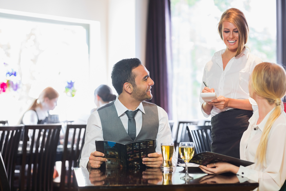 Smiling business people ordering dinner from waitress